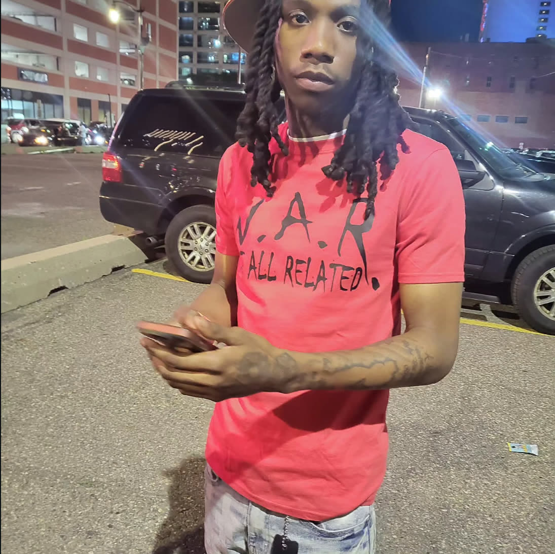 Man wearing a coral red W.A.R. — We All Related t-shirt